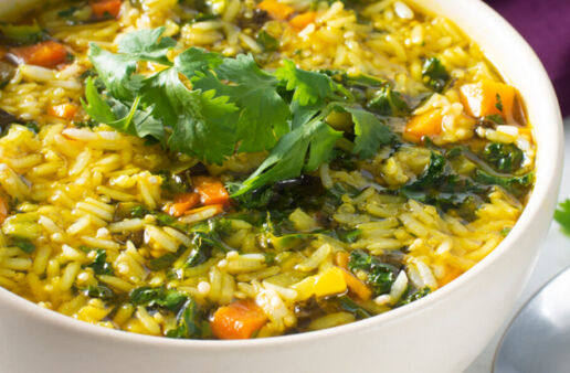 White bowl filled with soup, curried vegetables, jasmine rice and quinoa
