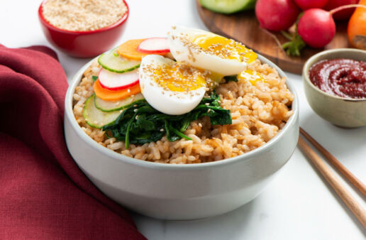 Bowl blanco con arroz de grano corto, vegetales encurtido y huevo escalfado