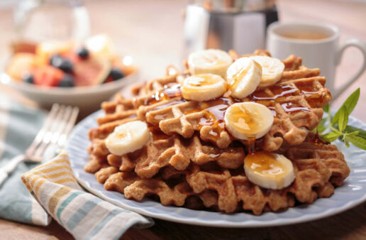 Stack of gluten free rice waffles topped with syrup and banana